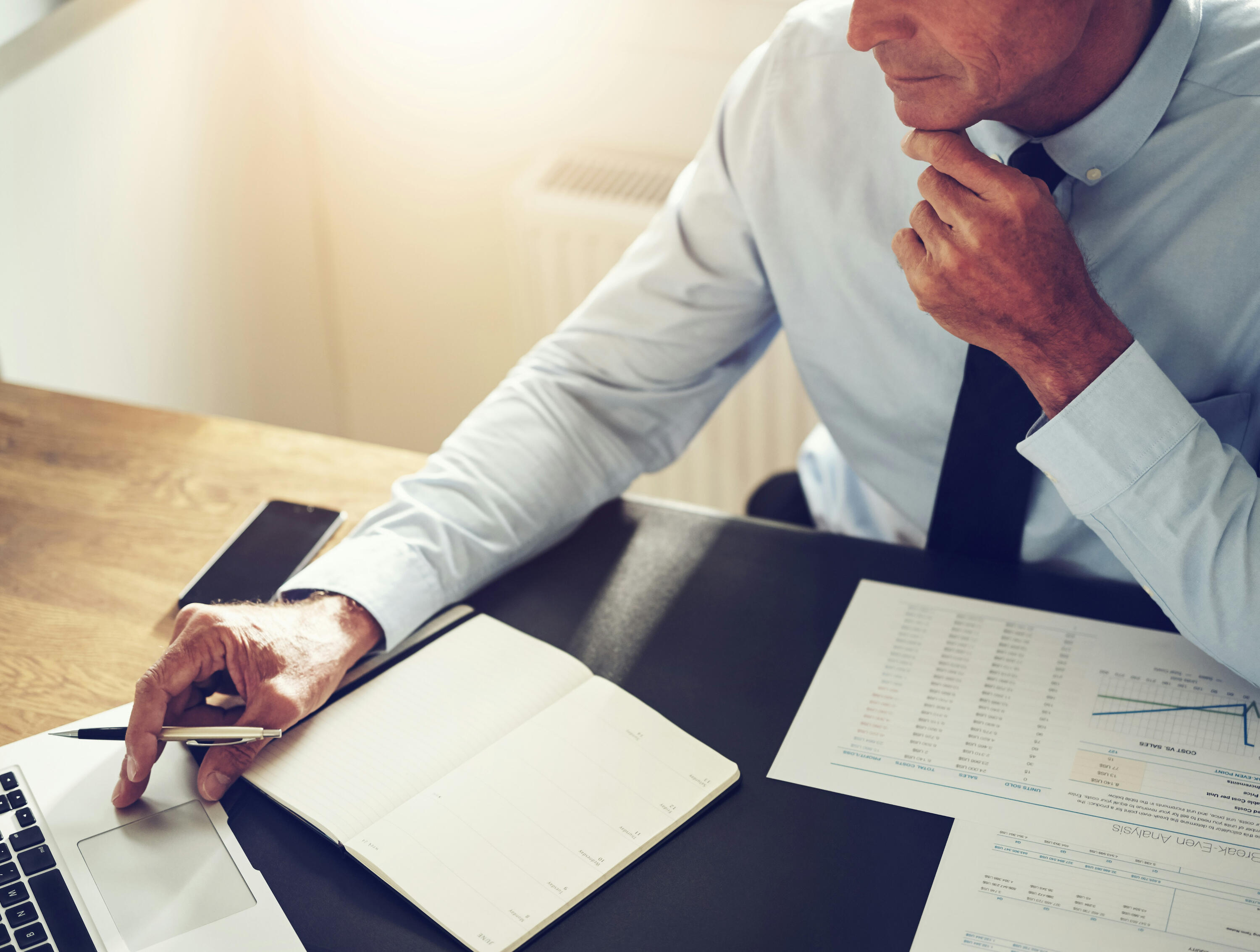 Working with The WhiteCliff Group a desktop layout with notebooks, coffee mug, and pencil case